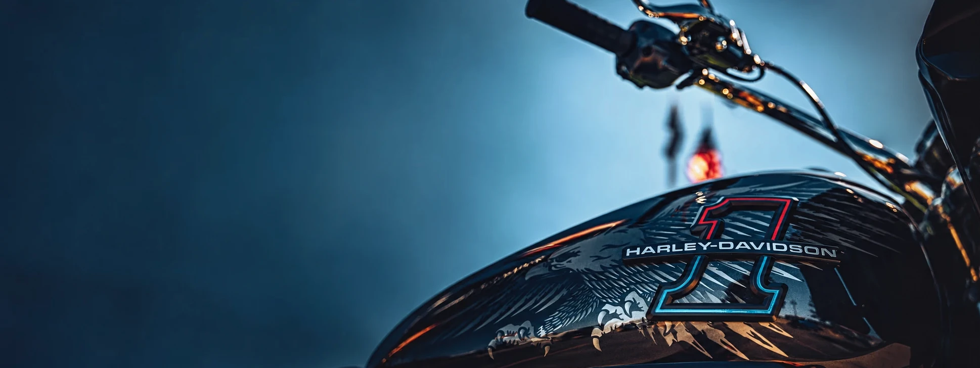 Custom motorcycle fuel tank and handlebar in a cool blue studio